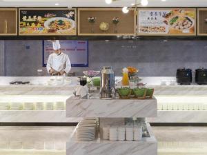 深圳Kyriad Marvelous Hotel·Shenzhen Dayun Center Baohe Road的厨师站在厨房的柜台后面