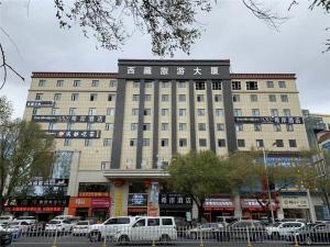 拉萨Xana Hotelle Lhasa Potala Palace Beijing Middle Road的一座大型建筑,前面有汽车停放