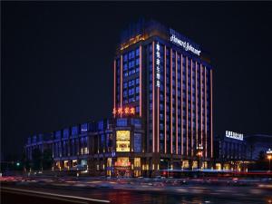 成都Howard Johnson Zunyue Hotel Chengdu的一座高大的建筑,晚上有灯