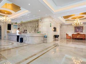 天津Vienna Hotel Tianjin Huaming的站在酒店大堂酒吧的男人