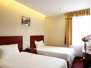 北京GreenTree Inn Beijing Daxing Xingye Street Liyuan Business Hotel的酒店客房设有两张床和窗户。