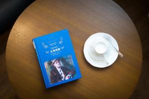 秦皇岛James Joyce Coffetel Qinhuangdao People Park Plaza的坐在桌边喝咖啡的书