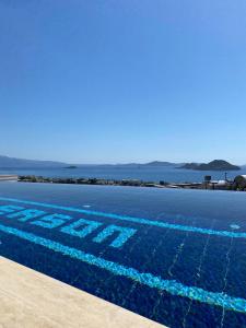 博德鲁姆Bodrum eaSon Villa & House 350m2 Full Sea View with Private Infinity Pool的海水前的蓝色游泳池