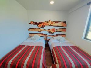 百内三塔Morrena Lodge的带条纹枕头的客房内的两张单人床