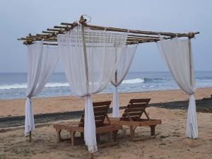 马尔万Raapan Beach Resort的海滩上的天篷和长凳