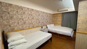 台北微笑逗点的一间设有两张床和石墙的房间