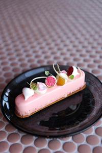 哥德堡Clarion Hotel Draken的一张桌子上黑色盘子上的粉红色蛋糕