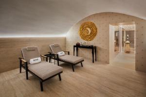 布尔诺巴瑟罗布尔诺宫殿酒店的一个带两把椅子、一张桌子和镜子的沙龙