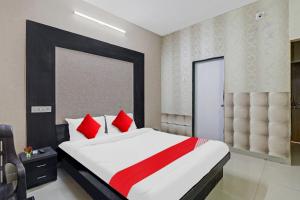艾哈迈达巴德OYO Hotel Sargam的一间卧室配有一张带红色枕头的大床