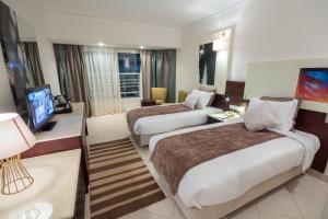 沙姆沙伊赫Sharming Inn Hotels - Couples and Families Only的酒店客房设有两张床和一台平面电视。