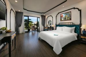 会安Bliss Hoi An Beach Resort & Wellness的卧室配有一张白色大床和一张书桌