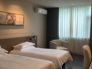 上海Jinjiang Inn Select Shanghai Pudong Airport的酒店客房,配有两张床和椅子