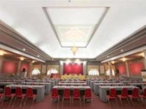 KalanganHotel Utami的大型客房配有桌子和红色椅子