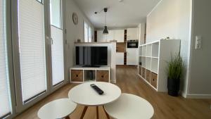 皮尔纳Ferienwohnung Gottleubapark Apartment的客厅配有2张白色桌子和电视