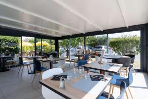 阿维尼翁阿维尼翁南部卡联达尔布里特酒店的餐厅设有桌椅和窗户。