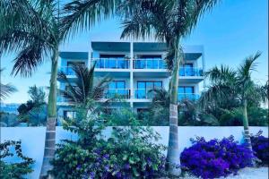 Long Bay HillsApartment Condominium Grace Bay Beach的公寓大楼拥有棕榈树和紫色的鲜花