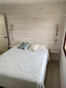 巴伊亚英格莱萨Hostal CKAIR的卧室内的一张白色床,卧室内有墙壁