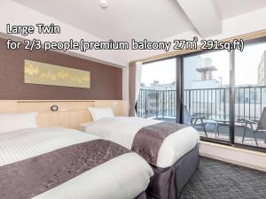 京都Hotel GOCO stay Kyoto Shijo Kawaramachi的带阳台的酒店客房内的两张床