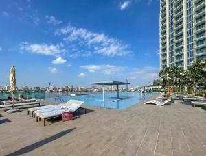 迪拜Elegant Luxury Apartment with Stunning Lake Views in Dubai Creek Harbour的一座带长椅的大型游泳池和一座建筑