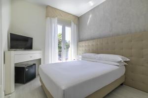 利多迪耶索罗Hotel Gallia & Resort的卧室配有白色的床和电视。