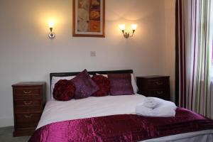 彼索普斯托福The George Hotel Stansted Airport的一间卧室配有一张带紫色床单和枕头的床。
