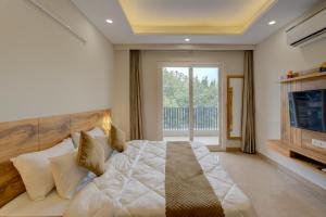 古尔冈1 BHK Serviced Apartments Near Millennium City Centre Gurugram with Private Washing Machine的一间卧室配有一张大床和电视