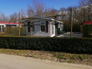 BaarlandFerienhaus für 6 Personen 1 Kind ca 41 qm in Baarland, Zeeland Küste von Zeeland的一条小白色房子,在街上设有门廊