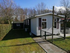 BaarlandFerienhaus für 6 Personen 1 Kind ca 41 qm in Baarland, Zeeland Küste von Zeeland的院子中带围栏的小白色房子