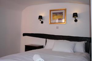 彼索普斯托福The George Hotel Stansted Airport的卧室配有白色床,墙上有两盏灯