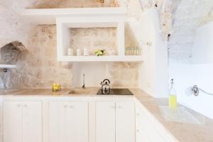 奥斯图尼Casa Zio Piero的白色的厨房配有白色橱柜和水槽