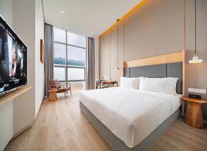 重庆Wuyu Hotel - Chongqing Liangjiang Happiness Plaza & Xingfu Square & GuangdianYuan metro的一间酒店客房,配有一张大床和一台平面电视