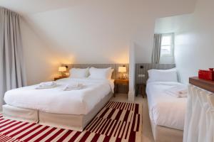 克诺克－海斯特Hotel Villa Bonnie的配有白色床单的酒店客房内的两张床