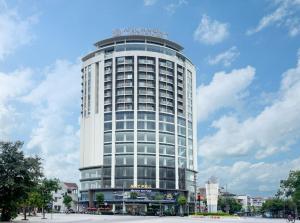 海阳Mandala Hotel & Suites Hai Duong的一座高大的白色建筑,上面有标志
