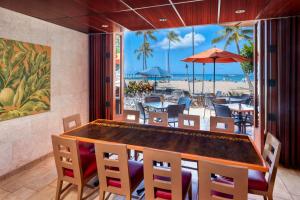 檀香山夏威夷威基基海滩希尔顿度假酒店的一个带桌椅的用餐室和一个海滩