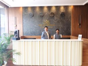 贾姆讷格尔The Sky Imperial Hotel Kailash的两个人站在一个柜台后面