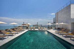 里约热内卢Windsor Marapendi Hotel的大楼内一个带椅子和遮阳伞的游泳池