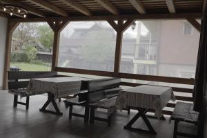 舒加塔格盐矿镇Pensiunea Magnolia的门廊设有桌子、长凳和大窗户