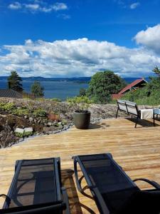 NesoddtangenOslo Fjord views with your own private beach hut at Flaskebekk的甲板上的两把长椅,享有水景