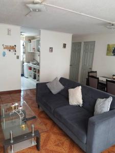 伊基克Departamento en Iquique A pasos de playa Cavancha的客厅配有蓝色的沙发和玻璃桌