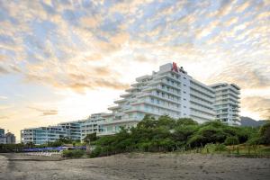 圣玛尔塔Santa Marta Marriott Resort Playa Dormida的海滩上的白色建筑,天空阴云