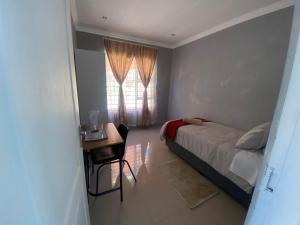 比勒陀利亚Mbobo Legacy Residence的一间卧室配有一张床、一张书桌和一个窗户。