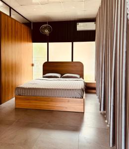 Phu YenHomestay Highland Garden的一间卧室配有带窗帘的木床