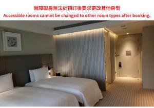 高雄Greet Inn 喜迎旅店的一张位于酒店房间的两张床,并刊登了无障碍客房的广告