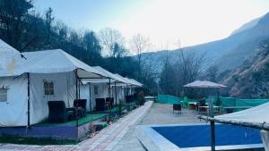 马拉里Zaranka Camps Kasol的一组配有桌子和游泳池的帐篷