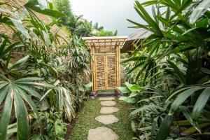 SelatMagic Hills Bali - Magical Eco-Luxury Lodge的穿过带木门的花园的路径