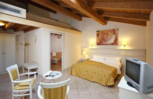 卡普里伽巴尔达酒店的一间卧室配有一张床、一台电视和一张桌子