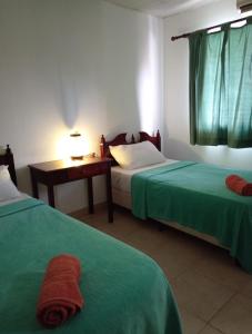 佩达西镇Residencial Santa Catalina Pedasi的酒店客房配有两张床、一张书桌和一张四柱床。