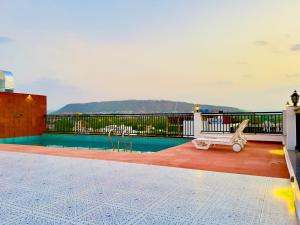 乌代浦Hotel De Glance Udaipur的阳台的游泳池,长凳