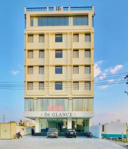 乌代浦Hotel De Glance Udaipur的一座黄色的建筑,前面有汽车停放