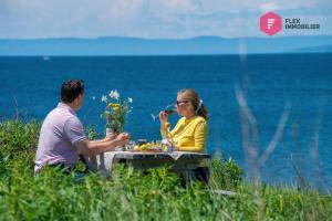 博纳旺蒂尔La Maison de l'Échouerie on Chaleur Bay Seaside的坐在海边桌子上的男人和女人